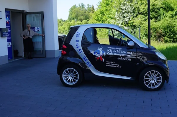 Meta Schneider am Eingang neben dem Fahrzeug des Kfz-Schilderdienstes